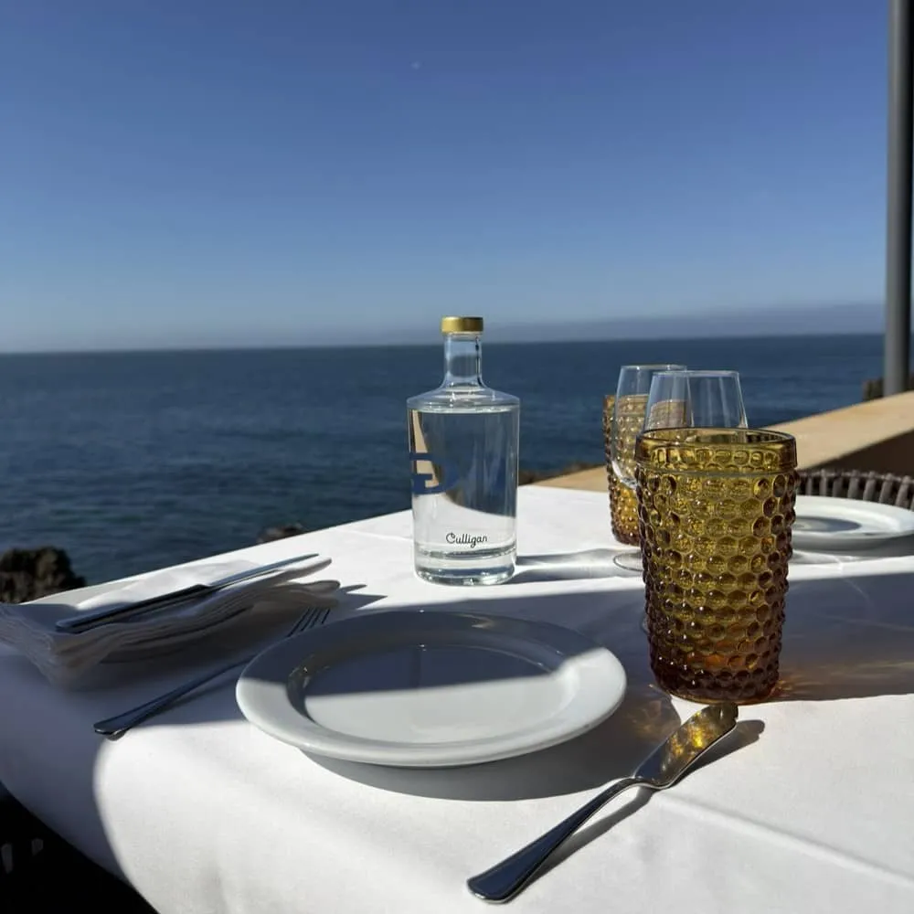 Mesa de restaurante à beira mar com uma garrafa de vidro personalizada Culligan AcquaRobot